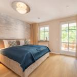Schlafzimmer mit Bett, Nachttisch und Balkonansicht.