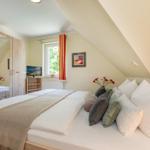 Schlafzimmer mit Dachschrägen, Bett, Kleiderschrank, Fenster und Fernseher.