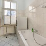 Badezimmer mit Badewanne, Dusche, Waschmaschine und Fenster.