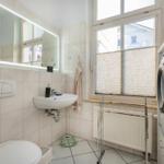 Badezimmer mit Waschmaschine, Spiegel und Fenster