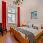 Schlafzimmer mit Holzbett, roten Vorhängen und Holzmöbeln.