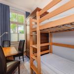 Zimmer mit Doppelstockbett, Schreibtisch und Fenster mit Blick.