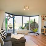 Wohnzimmer mit Sofa, TV und Terrasse mit Hängesessel.