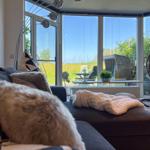 Wohnzimmer mit Sofa, Decke und Blick auf Garten und Himmel