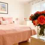 Schlafzimmer mit Bett, Blumen und Bild an der Wand.