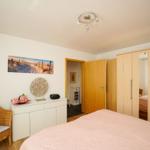Schlafzimmer mit Bett, Schrank und Stuhl. Wandbild zeigt Strand.