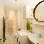 Badezimmer mit Dusche, Waschmaschine und Spiegel.
