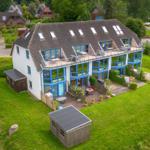 Modernes Haus mit großem Garten und Terrasse mit blauen Fenstern.