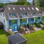 Moderne Villa mit blauen Fenstern und Dachterrasse. Großer Garten mit Terrasse und Grillplatz.