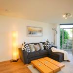 Ein Wohnzimmer mit grauem Sofa, Holztisch und Glasfront zur Terrasse.