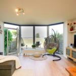 Wohnzimmer mit Sitzgelegenheiten, Fernseher und Blick auf die Terrasse.