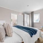 Schlafzimmer mit Bett, Kleiderschrank und Fenster. Holzboden und Wandfarbe.