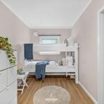 Schlafzimmer mit Doppelstockbett, Schrank und Fenster. Holzboden und runder Teppich.