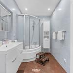 Badezimmer mit Dusche, Waschbecken und Spiegel. Holzstufen und Handtücher.