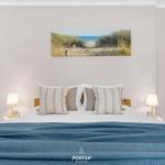 Schlafzimmer mit Bett, Kissen und Wandbild. Zwei Nachttische mit Lampen.