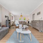 Wohnzimmer mit Sofa, Kamin und Holzboden. Tisch mit Spielen und Wandbildern.