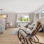 Wohnzimmer mit Holzboden, Sessel, Couch und Fenster. Dekoration mit Schiffsmotiven.