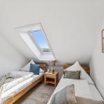 Zwei Betten unter Dachschrägen mit Dachfenster und Bildern an der Wand.