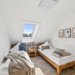 Zwei Betten in einem Dachzimmer mit Dachfenster und Wandbildern.