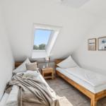 Zimmer mit zwei Betten, Dachfenster und Wandbildern.