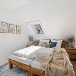 Schlafzimmer mit Dachschrägen, Dachfenster und Holzbett. An den Wänden hängen drei Bilder.