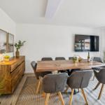 Esszimmer mit Holztisch, grauen Stühlen und Fernseher an der Wand.