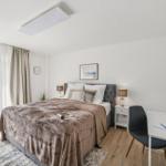 Schlafzimmer mit Bett, Schreibtisch und Terrassentür.
