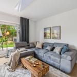 Wohnzimmer mit grauem Sofa, Holztisch und Blick auf die Terrasse.