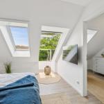 Schlafzimmer mit Dachfenstern, TV und Blick auf Balkon