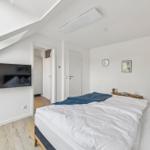 Schlafzimmer mit Bett, Fernseher und Holzboden