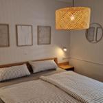 Doppelbett mit Streifenbezug, Wandbilder und Holz-Nachtisch. Rundspiegel und Hängelampe.