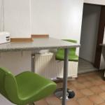 Küchenbereich mit grünen Barhockern und Arbeitsplatte.