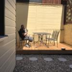 Mann mit Hund sitzt auf Terrasse mit Tisch und Stühlen.