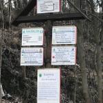 Wanderwegweiser im Wald mit Entfernungen zu Sehenswürdigkeiten.