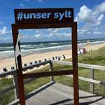 Holzgestell mit Schild #unser sylt auf Strandpromenade