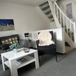 Wohnzimmer mit Sofa, Sessel und Tisch unter Treppe.