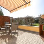 Terrasse mit Sonnenschutz, Tisch, Stühlen und Blick auf Garten