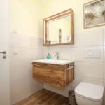 Badezimmer mit Holzwaschbecken, Spiegelschrank und Toilette.