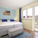 Schlafzimmer mit Doppelbett, Fenster und Balkon. Wandbild und Nachttische.