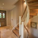 Eingang mit Holztreppe, Tisch mit Vasen und Wandbild.