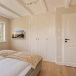 Schlafzimmer mit Bett, Kleiderschrank und Fenster mit Blick auf Grün.