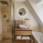 Dusche, Waschbecken und Badewanne in einem Dachbodenbad mit Fenster.