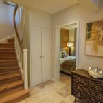 Haus mit Holztreppe, Schrank und Blick in Schlafzimmer mit Bett und Lampe.