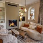 Wohnzimmer mit Kamin, Sofa, Sessel und Glasfront zur Terrasse.