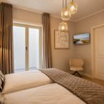 Schlafzimmer mit Bett, Lampe, Fenster und Deckenleuchte.