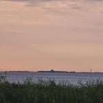Sonnenuntergang über dem Wasser mit Insel und Turm im Hintergrund.
