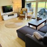 Wohnzimmer mit Sofa, Fernseher und Terrasse