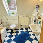 Badezimmer mit Dachfenster, Toilette, Waschbecken und blau-weißem Fliesenboden.