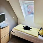 Schlafzimmer mit Dachschrägen, Bett, TV und Fenster.
