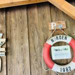 Rettungsring mit Parkplatzschild an Holzwand. Holzschild mit Segelschiffmotiv.